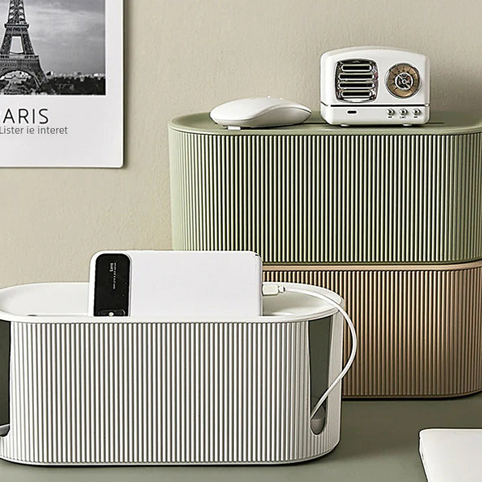 Desk setup with striped storage boxes and a white electronic device on a neutral background.